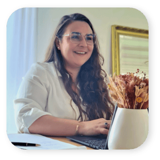 femme souriante assise à un bureau travaillant sur un ordinateur